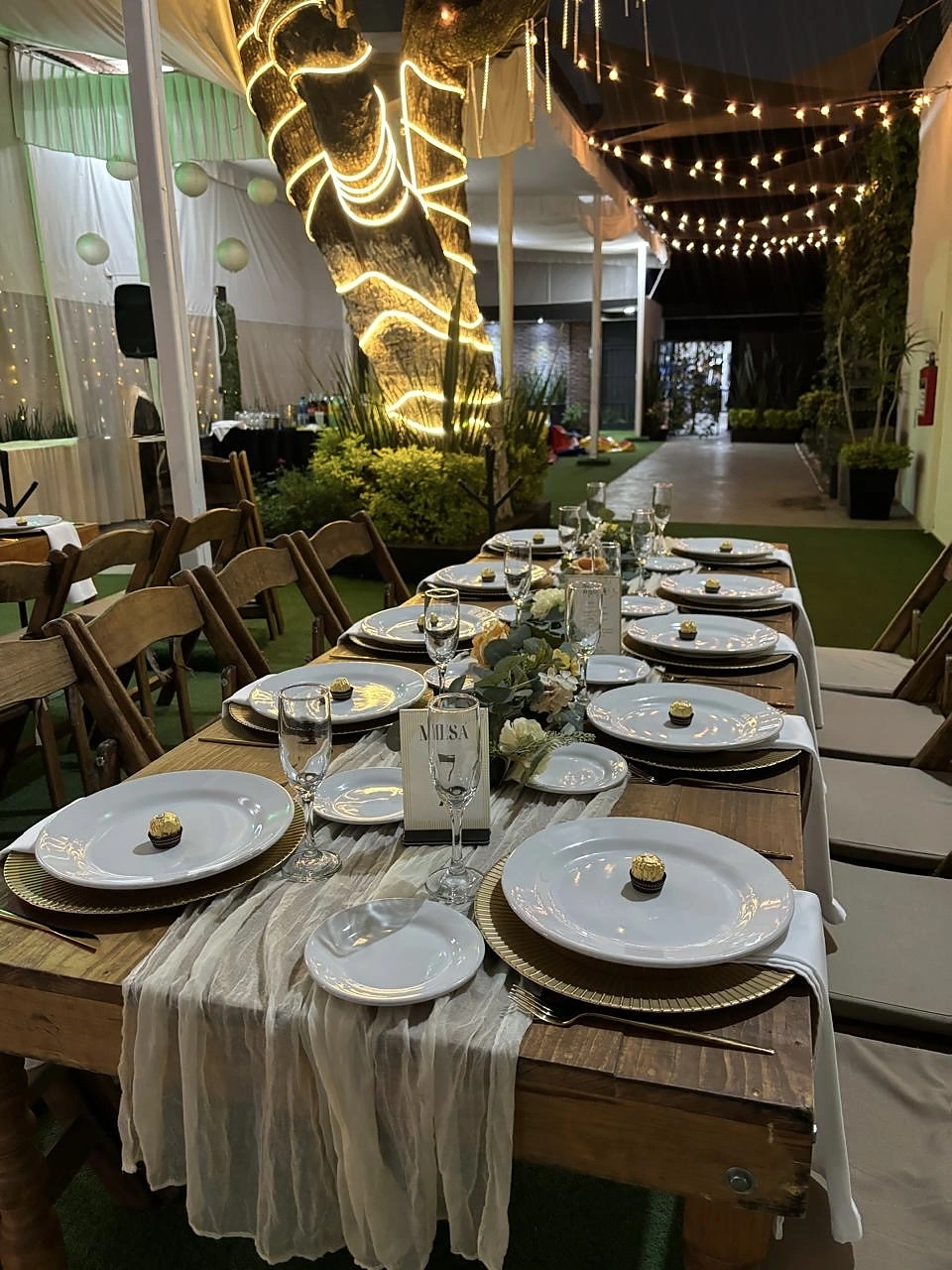 Mesa de madera con vajilla blanca y árbol iluminado